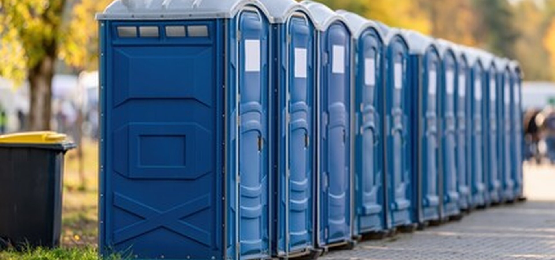 Row of standard blue portable toilets lined up for a large gathering